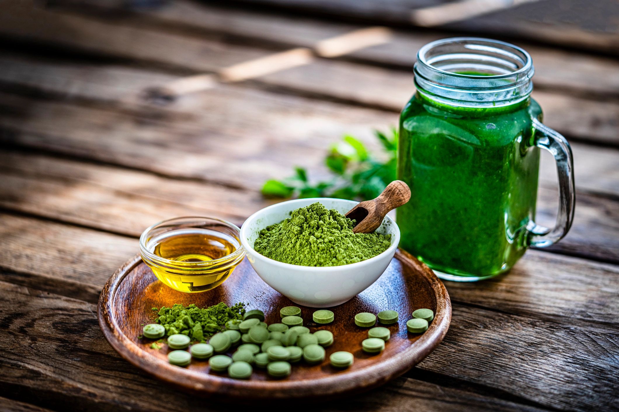 Moringa powder and capsules with a green detox drink on a rustic wooden table