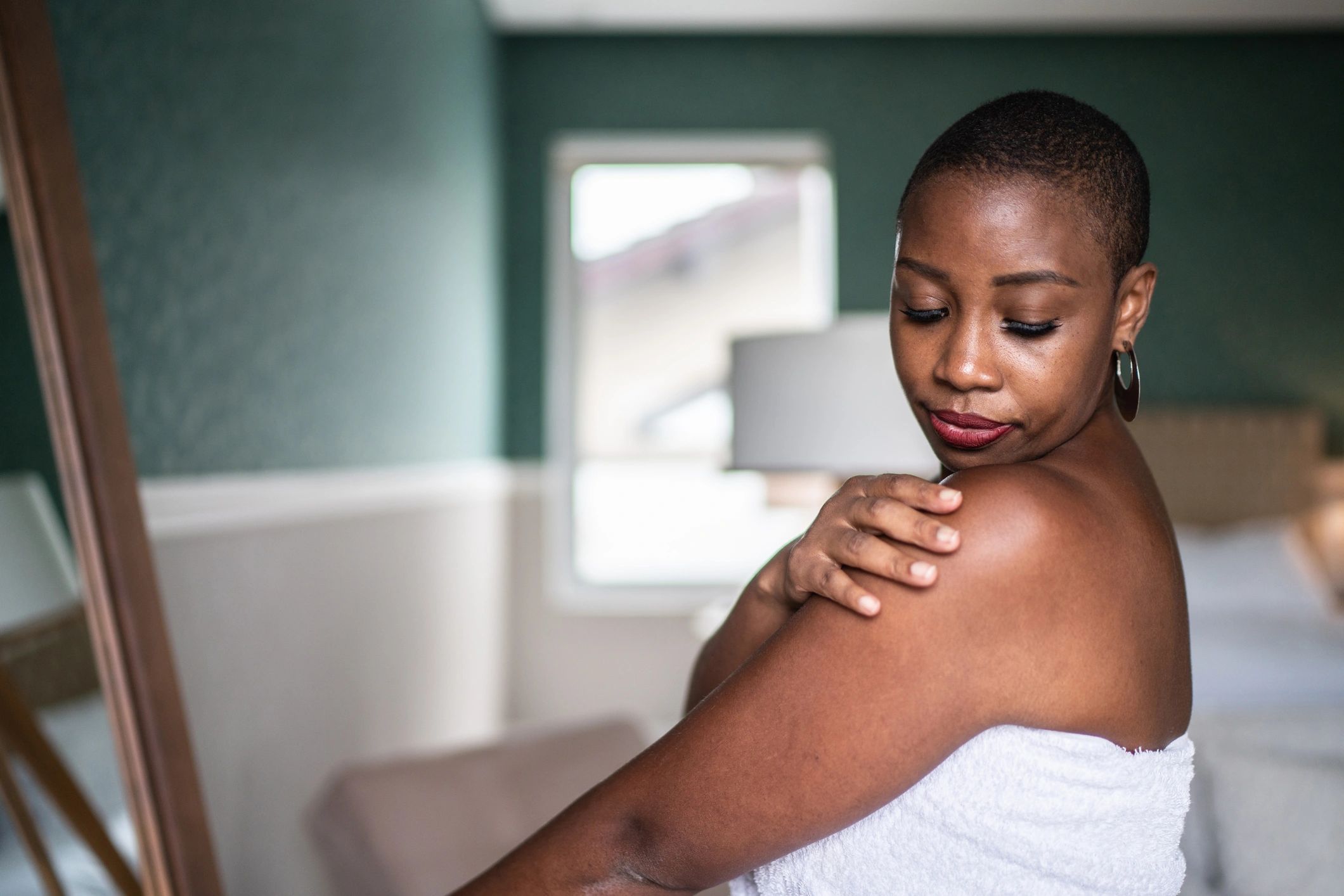 Woman practicing self-care with skincare in a towel