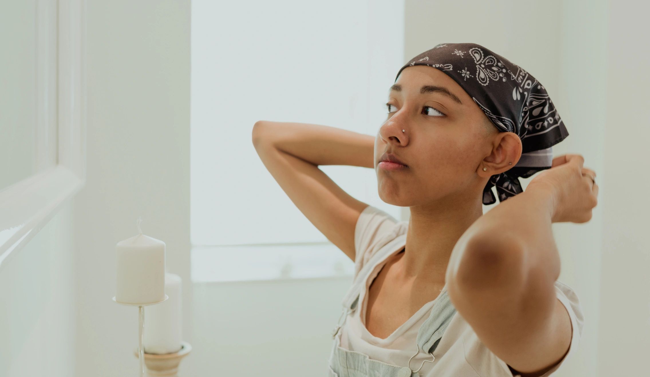 Woman tying a bandana in front of a mirror, preparing for the day