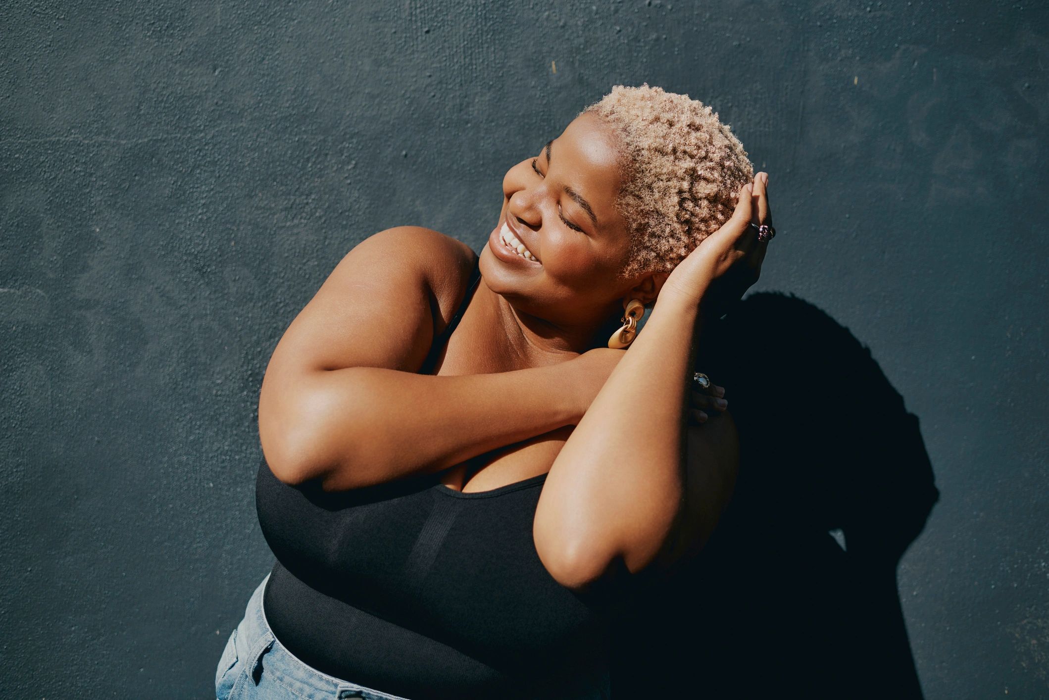 Woman with natural curly hair smiling, representing confident holistic hair care