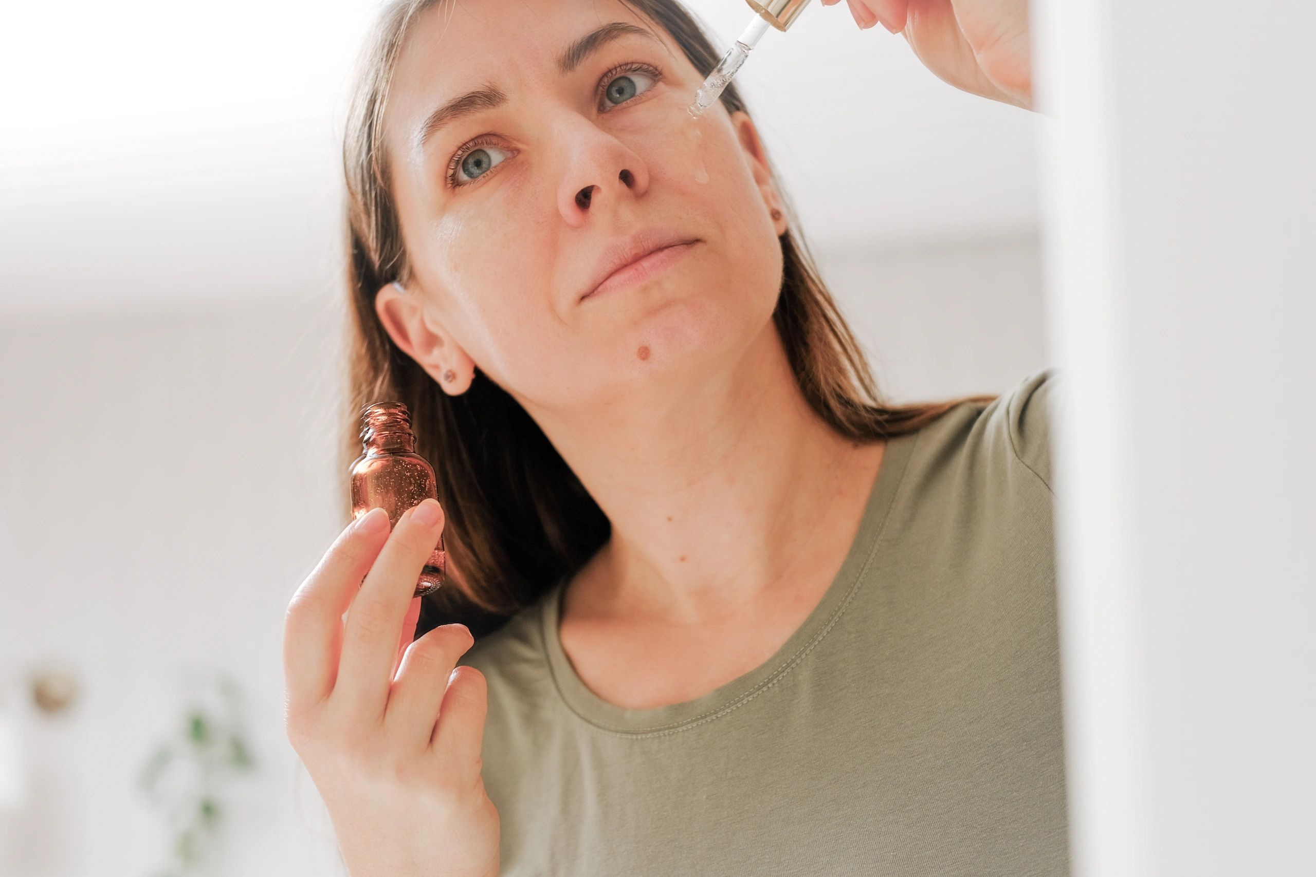 Woman applying facial oil serum with a dropper